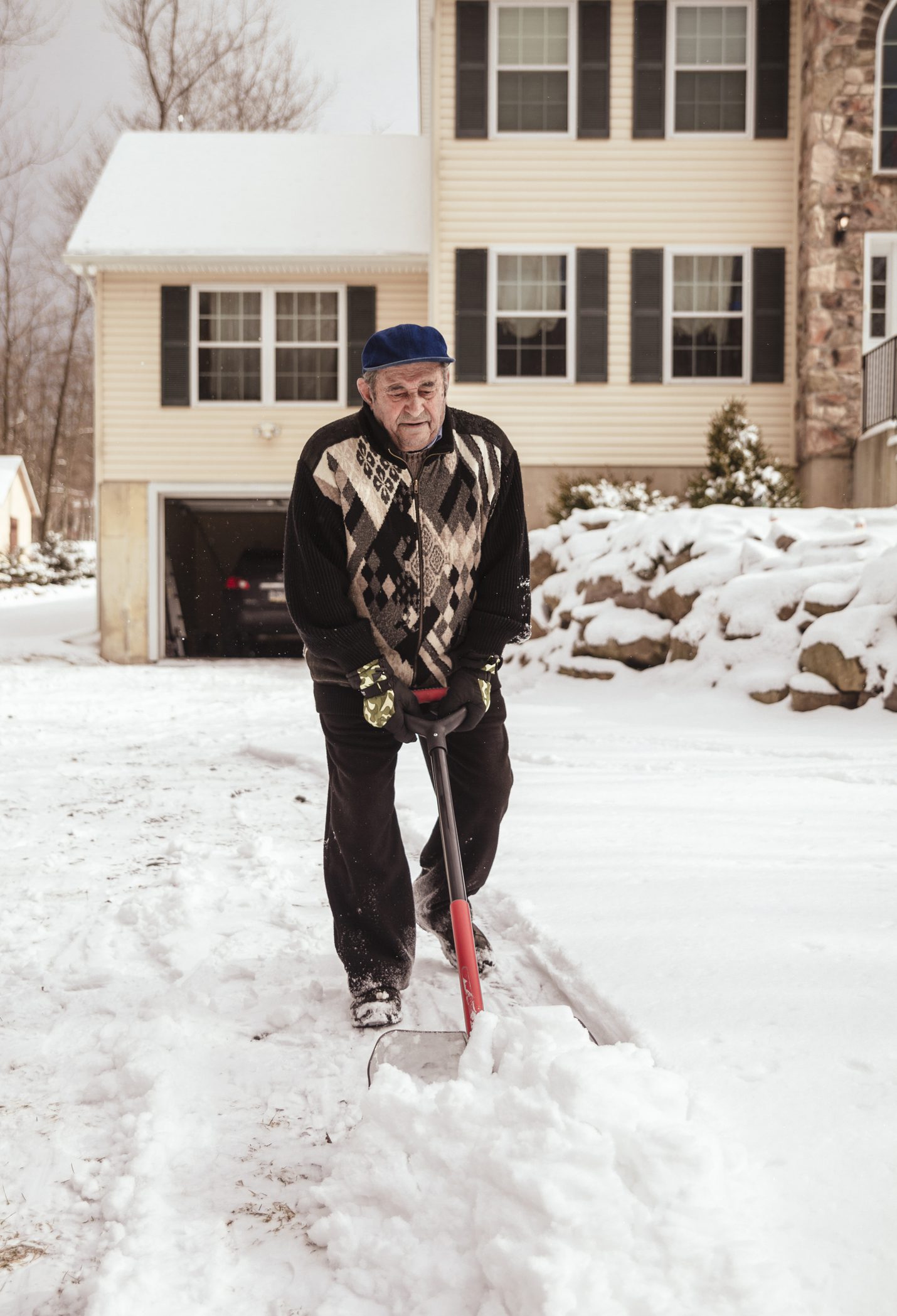 Elderly man shoveling snow in driveway